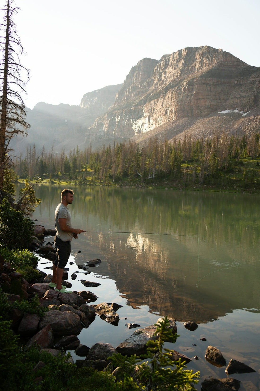 A man standing on a rocky shore next to a lake