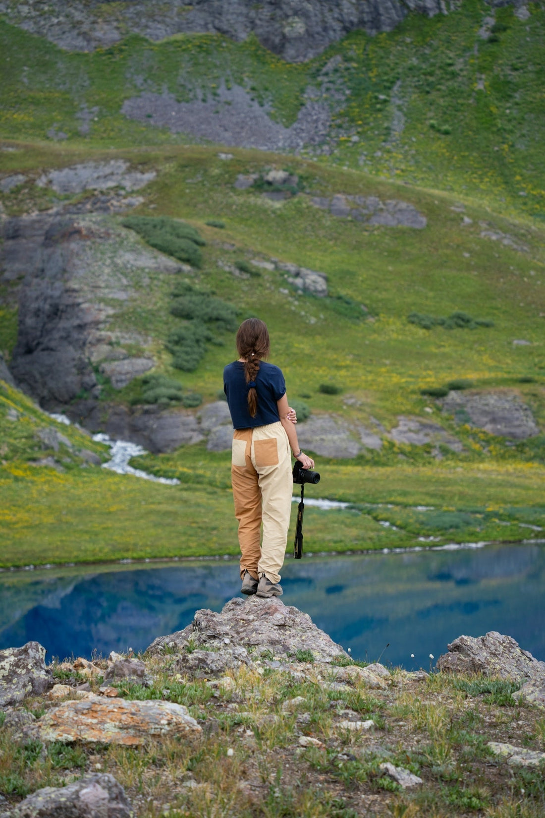 A man standing on top of a rock next to a lake