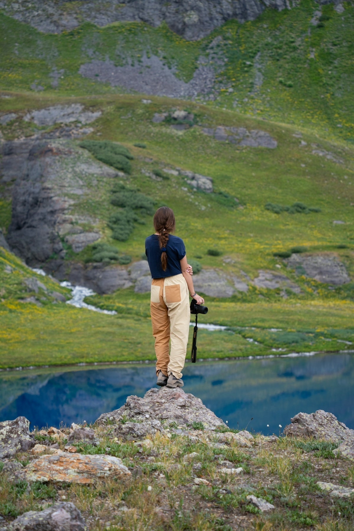 A man standing on top of a rock next to a lake