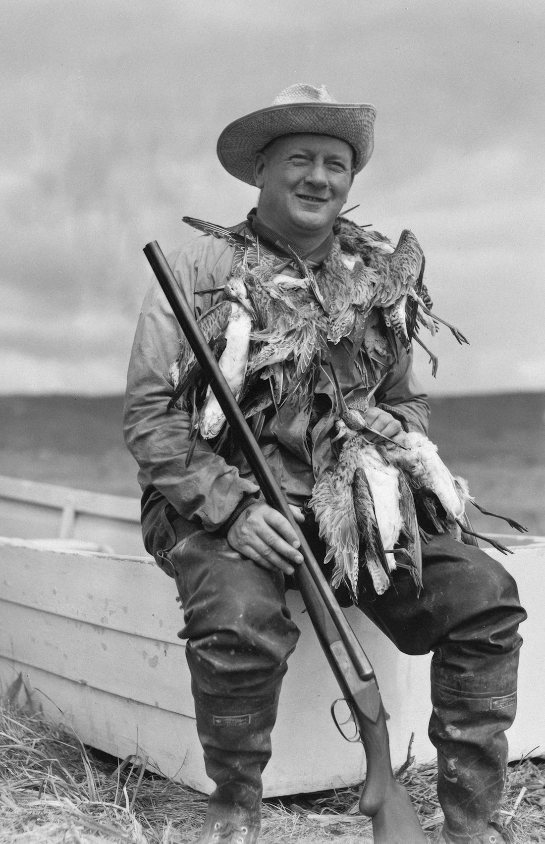 Hunter in hat with shotgun and game sits in boat
